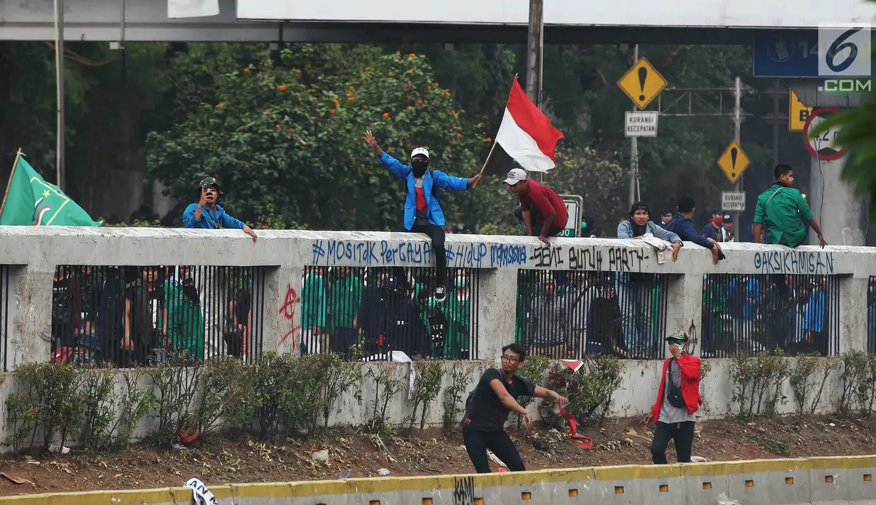 Mahasiswa mengibarkan bendera Merah Putih saat demonstrasi menolak pengesahan RUU KUHP dan revisi UU KPK di depan Gedung DPR, Jakarta, Selasa (24/9/2019). Mahasiswa lari tunggang langgang setelah aparat kepolisian menembakkan gas air mata dan water cannon. (Liputan6.com/JohanTallo)