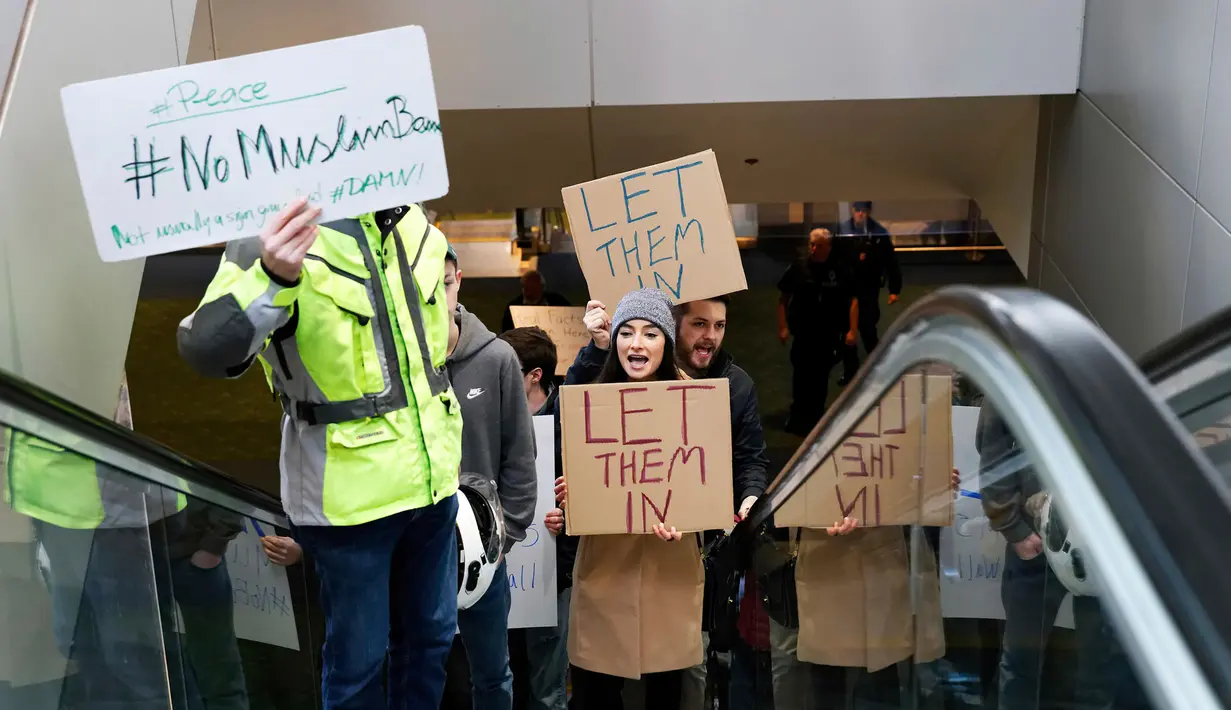Massa menggelar aksi protes di Bandara Internasional Portland, Sabtu (28/1). Massa berkumpul di bandara-bandara AS menolak kebijakan Donald Trump yang melarang warga dari 7 negara muslim masuk ke Amerika Serikat. (Mike Zacchino/The Oregonian/AP)