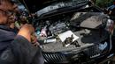 Petugas melihat bagian mesin dari mobil mewah bodong yang berhasil diamankan petugas Satlantas Jakarta Utara dalam operasi yang digelar mulai 27 Mei hingga 11 Juni 2015, Jakarta, Kamis (28/5/2015). (Liputan6.com/Faizal Fanani)