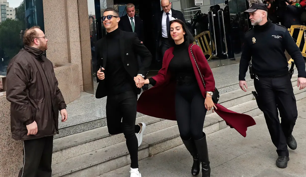 Pemain Juventus Cristiano Ronaldo menggandeng kekasihnya Georgina Rodriguez saat meninggalkan pengadilan di Kota Madrid, Spanyol, Selasa (22/1). Kapten Timnas Portugal itu terancam dua tahun penjara dan denda 18,8 juta Euro. (AP Photo/Manu Fernandez)