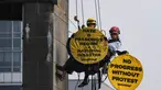 Aktivis Greenpeace Indonesia bergelantungan di Patung Selamat Datang sambil membentangkan poster berisi pesan protes di kawasan Bundaran Hotel Indonesia, Jakarta, Selasa (20/10/2026). Aksi tersebut digelar bertepatan dengan dua tahun pelantikan Presiden Prabowo Subianto. Para aktivis mendesak pemerintah mengambil langkah untuk mengatasi krisis iklim yang kian memburuk dan kenaikan biaya hidup. (BAY ISMOYO/AFP)