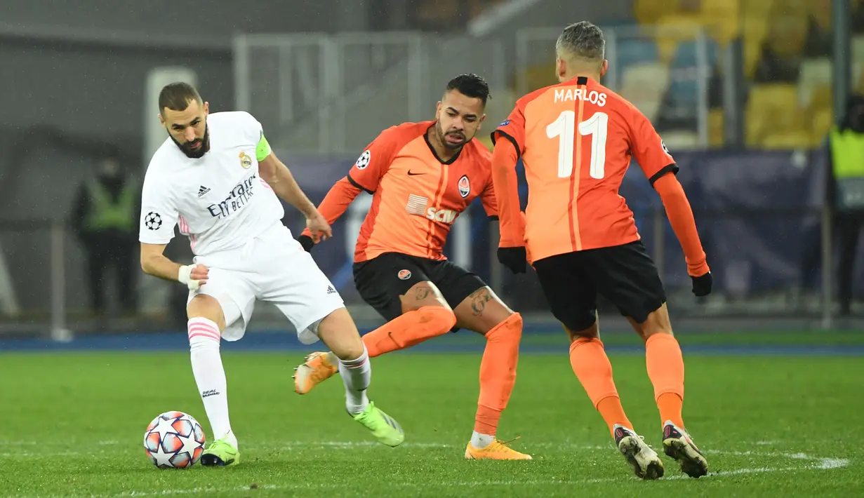 Penyerang Real Madrid, Karim Benzema (kiri) berebut bola dengan pemain Shakhtar Donetsk, Dentinho (tengah) dan Marlos pada matchday kelima Grup B Liga Champions di NSK Olimpiyskiy, Kiev, Rabu (2/12/2020) dini hari WIB. Real Madrid tumbang 0-2 di markas Shakhtar Donetsk.  (Sergei SUPINSKY / AFP)