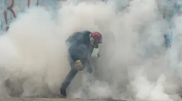 Asap gas air mata menyelimuti seorang demonstran saat aksi  menentang Presiden Venezuela Nicolas Maduro, di Caracas, kamis (20/4). Tiga orang dikabarkan tewas dalam aksi demonstrasi tersebut.  (AFP PHOTO / Juan BARRETO)