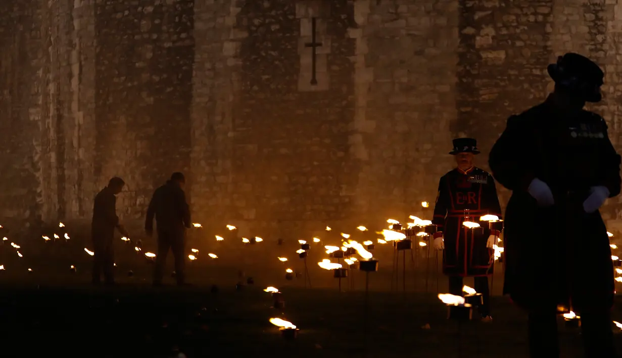 Yeoman Warders atau 'Beefeaters' menyalakan ribuan lilin di parit kering Tower of London, Inggris, Selasa (6/11). Nyala lilin membentuk instalasi yang disebut 'Beyond the Deepening Shadow: The Tower Remembers'. (AP Photo/Alastair Grant)