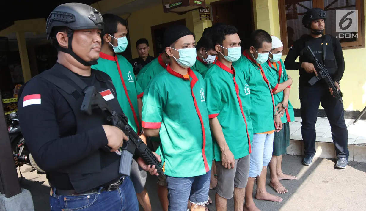 Petugas mengawal tersangka saat  pemusnahkan barang bukti miras dan narkoba di halaman Polsek Palmerah, Jakarta Barat, Senin (14/5). Pemusnahan dilakukan untuk menciptakan suasana kondusif menjelang bulan suci Ramadan. (Liputan6.com/Arya Manggala)