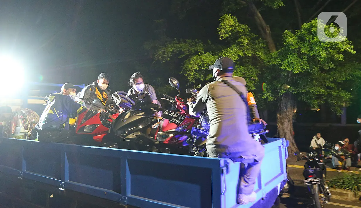 Petugas mengangkut sejumlah motor yang berhasil diamankan dalam patroli penegakan protokol kesehatan COVID-19 di Jalan Veteran, Jakarta Pusat, Sabtu (26/12/2020). Operasi gabungan itu dilakukan menyusul meningkatnya penyebaran COVID-19 di Ibu kota. (Liputan6.com/Herman Zakharia)