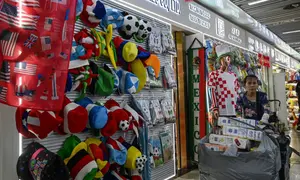 Topi dan barang dagangan lainnya untuk Piala Dunia 2026 dipajang di sebuah toko di Pasar Perdagangan Internasional Yiwu di Yiwu, provinsi Zhejiang, China timur, pada 17 September 2025. Kekhawatiran tarif merugikan pesanan barang dagangan Piala Dunia di pabrik rajutan Shang Yabing di China, di mana rak-rak syal menampilkan logo tim nasional dari Irlandia hingga Tanzania. Produsen di pusat ekspor China, Yiwu, biasanya sudah dibanjiri pesanan Piala Dunia menjelang turnamen sepak bola musim panas mendatang, yang kali ini diselenggarakan oleh Amerika Serikat, Meksiko, dan Kanada. (Jade GAO/AFP)