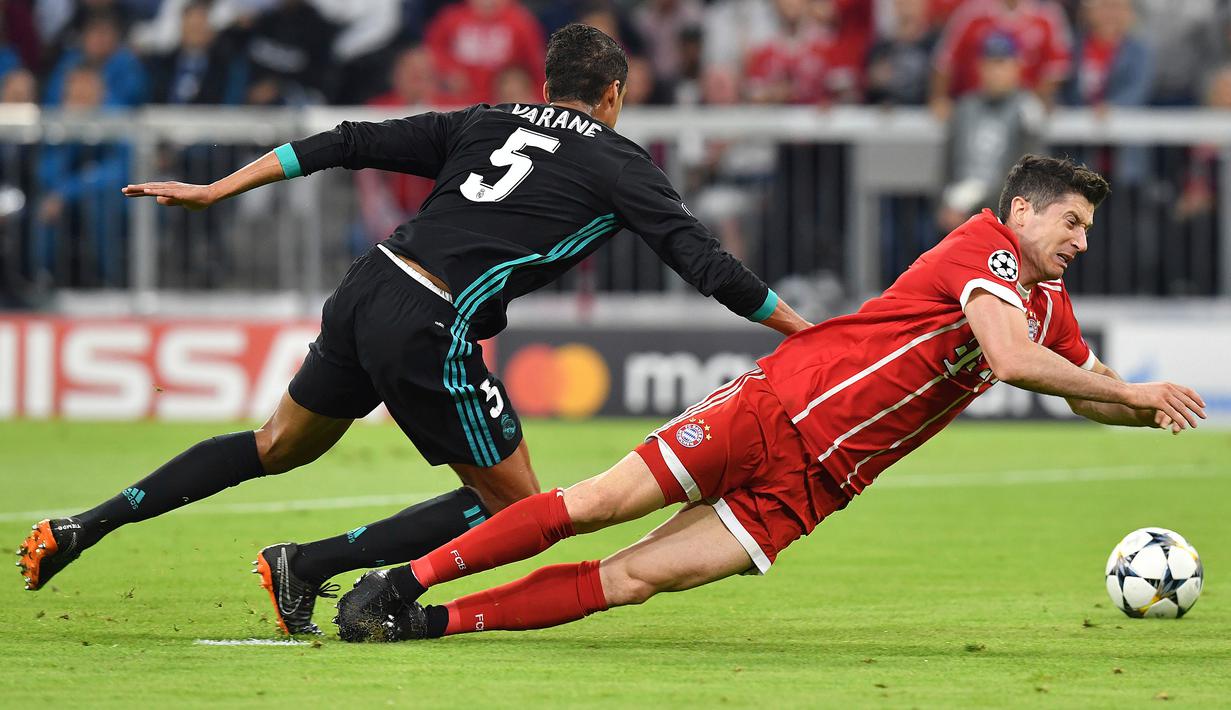 Pemain Bayern Munchen, Robert Lewandowski berebut bola dengan pemain Real Madrid, Raphael Varene pada leg pertama semifinal Liga Champions di Allianz Arena, Rabu (25/4). Real Madrid berhasil menumbangkan Bayern Munchen 2-1. (AP/Matthias Schrader)