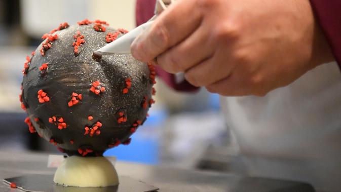 Pembuat cokelat, Jean-François Pre menyiapkan telur paskah berbentuk seperti Virus Corona di tokonya di Landivisiau, Prancis, 7 Maret 2020. Cokelat ini terbuat dari cokelat putih yang diberikan pewarna hitam serta dipadukan dengan kacang almond yang diwarnai merah. (Damien MEYER/AFP)