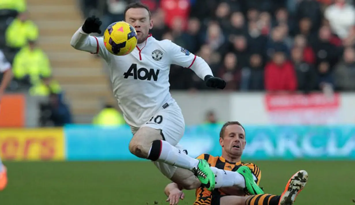 Pemain Hull City terpaksa harus melakukan pelanggaran untuk menghentikan laju penyerang Manchester United, Wayne Rooney dalam laga lanjutan Liga Premier di KC Stadium, Kamis (26/12/2013) malam WIB.(AFP/Lindsey Parnaby)
