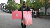 Penggemar membawa kantong plastik usai berbelanja dari toko pop-up BTS di Distrik Gangnam, Seoul, Korea Selatan, Jumat (18/10/2019). Ada sekitar 200 lebih jenis merchandise baru ditampilkan di ruang pamer. (Jung Yeon-je/AFP)