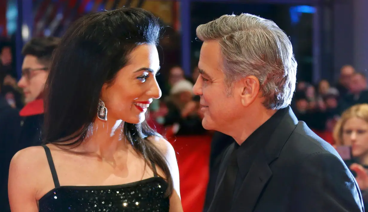 Aktor AS George Clooney dan istrinya, Amal Alamuddin berpose untuk fotografer saat tiba di karpet merah pemutaran film "Hail, Caesar!" pada pembukaan Berlin International Film Festival ke-66 di Berlin, Jerman, Kamis (11/2). (REUTERS/Fabrizio Bensch)