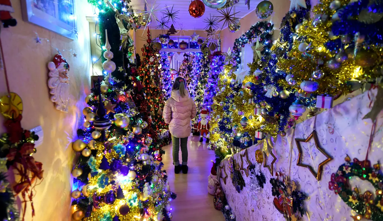 Seorang gadis berdiri di antara pohon-pohon Natal yang menghiasi rumah keluarga Thomas Jeromin di Rinteln, Jerman, Minggu (8/12/2019). Thomas Jeromin memenuhi rumahnya dengan 350 pohon Natal di hampir tiap sudut rumah, mulai dari ruang tamu, dapur sampai kamar mandi. (Ina FASSBENDER/AFP)