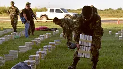 Petugas meletakan satu ton kokain dalam paket yang disita di lokasi Baures saat jumpa pers di Trinidad, El Beni, Bolivia (19/7). Obat terlarang tersebut diduga akan dikirim ke Brasil. (AFP Photo/Ar/Aizar Raldes)