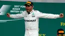 Lewis Hamilton merayakan kemenangan diatas podium setelah memenangkan GP Inggris di sirkuit Silverstone, (16/7). Kemenangan Hamilton ini sekaliguas menyamai rekor dua pebalap legendaris Formula 1 (F1), Jim Clark dan Alain Prost. (AP Photo/Frank Augstein)