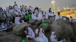 Umat Muslim berdoa di puncak bukit berbatu yang dikenal sebagai Jabal Rahmah atau Gunung Rahmat, di Dataran Arafah, selama ibadah haji tahunan di dekat kota suci Mekah, Arab Saudi, Selasa 26 Mei 2026. (AP Photo/Altaf Qadri)