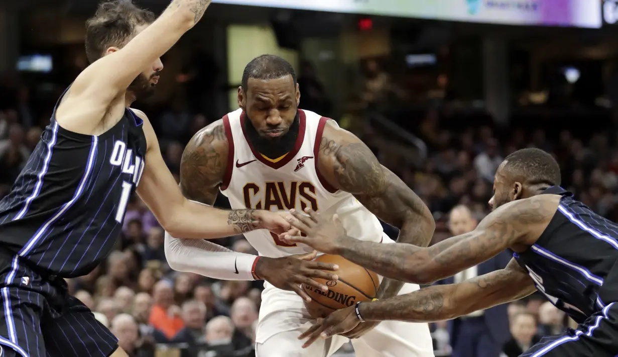 Pemain Cleveland Cavaliers, LeBron James (tengah) berusaha melewati kepungan dua pemain Orlando Magic pada lanjutan NBA basketball game di Quicken Loans Arena, (18/1/2018). Cavaliers menang 104-103. (AP/Tony Dejak)