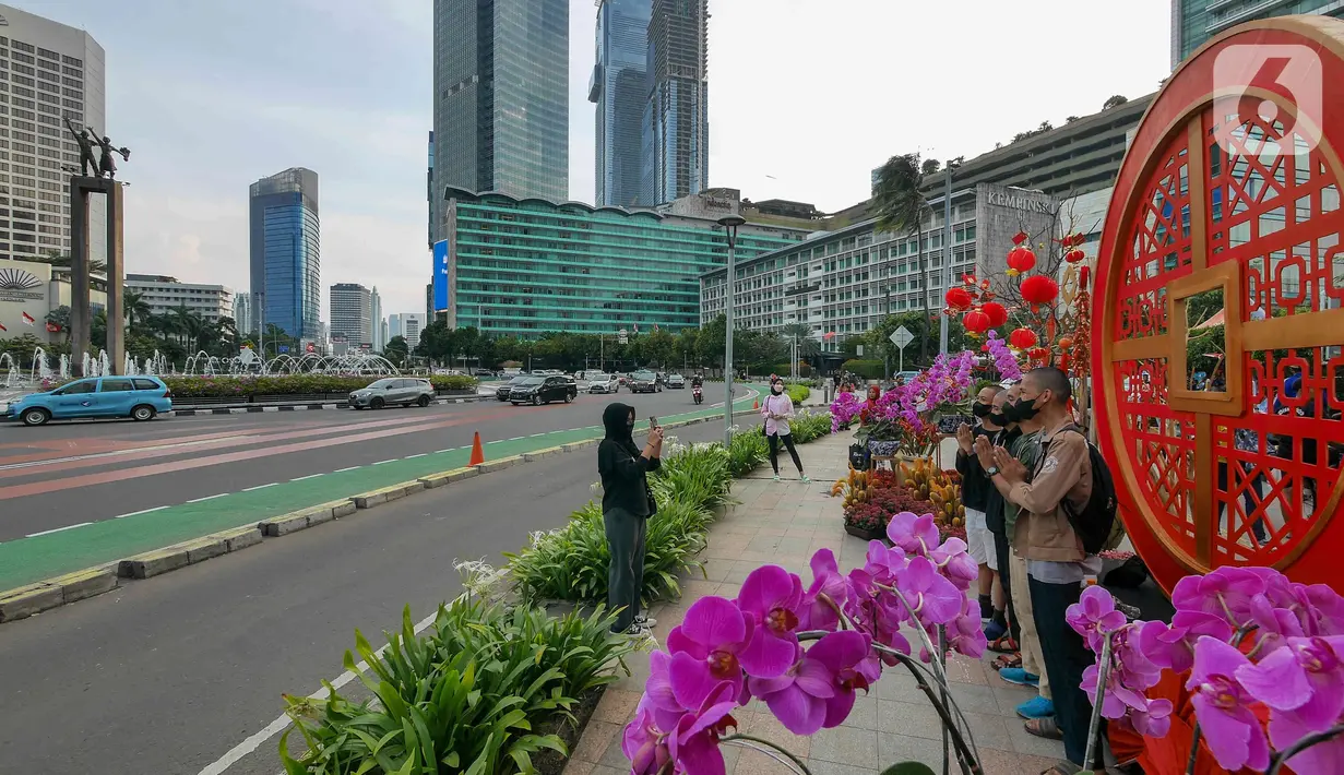 Warga berfoto di depan ornamen dengan nuansa Imlek di kawasan Bundaran HI, Jakarta, Sabtu (29/1/2022). Ornamen yang didominasi warna merah dan emas ini dipasang dalam rangka menyambut perayaan Tahun Baru Imlek 2573, yang jatuh pada 1 Februari mendatang. (Liputan6.com/Herman Zakharia)