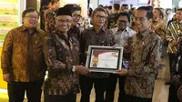 Presiden Jokowi menerima penghargaan sebagai pelapor gratifikasi dengan nilai terbesar yang ditetapkan menjadi milik negara dari Ketua KPK, Agus Rahardjo pada peringatan hari Antikorupsi Dunia, Jakarta, Senin (11/12). (Liputan6.com/Angga Yuniar)