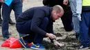 Pangeran William saat membantu anak-anak sekolah membersihkan sampah di pantai Newborough di Wales (8/5). Pangeran William dan Kate Middleton melakukan kunjungan ke pantai Newborough untuk membersihkan sampah bersama anak-anak sekolah. (Reuters/Phil Noble)