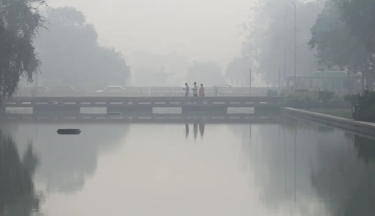 Pejalan kaki berjalan di sepanjang jalan dekat Gerbang India (tidak terlihat) di tengah kabut asap tebal di New Delhi, Kamis (3/11/2022). Tingkat partikel paling berbahaya yaitu PM2.5 adalah 588 per meter kubik pada Kamis pagi, menurut pemantauan IQAir. Partikel PM2.5 sangat kecil sehingga dapat memasuki aliran darah. (Money SHARMA / AFP)