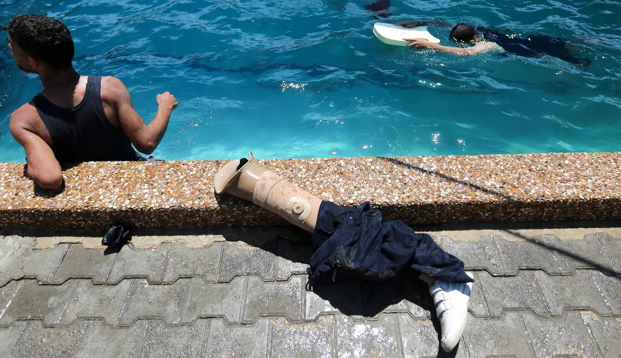 Kaki palsu terlihat di dekat kolam renang ketika warga Palestina berlatih di bawah instruksi Majdi al-Tatar di Gaza (30/7/2019). Tatar, yang kehilangan kaki kanannya akibat kecelakaan pada masa kecilnya, melatih warga Palestina yang diamputasi selama konflik dengan Israel. (AFP Photo/Mahmud Hams)