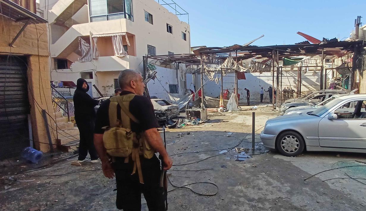 Serangan ini terjadi di tengah meningkatnya kekerasan di wilayah tersebut dan dapat memberikan tekanan pada gencatan senjata yang rapuh antara Israel dan Hamas di Gaza. Tampak dalam foto, seorang anggota Hamas berjaga di lokasi serangan Israel pada Selasa malam yang menghantam kamp pengungsi Palestina Ein el-Hilweh di kota pelabuhan Sidon, Lebanon, pada Rabu 19 November 2025. (AP Photo/Mohammed Zaatari)