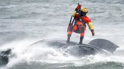 Penyelam Penjaga Pantai AS diturunkan dari helikopter untuk menarik tubuh pengendara mobil yang terjebak dalam arus deras di tepi Air Terjun Niagara, New York, AS, 8 Desember 2021. Masih belum jelas apakah pengemudi masuk ke sungai dengan sengaja atau tidak. (AP Photo/ Jeffrey T. Barnes)