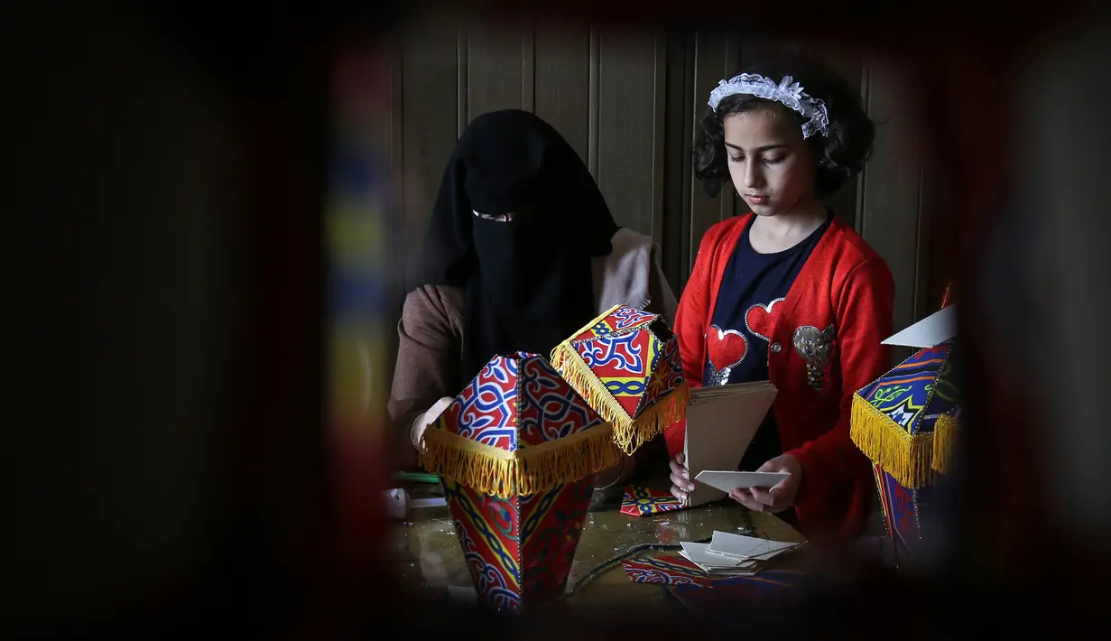 Anggota keluarga Palestina al-Yaqoubi berkumpul di sekitar meja membuat lentera bulan suci Ramadan untuk dijual selama penerapan lockdown di Khan Yunis, di Jalur Gaza selatan pada 15 April 2020. Karena pandemi Covid-19, keadaan berubah dan tradisi Ramadan pun tidak akan ada. (SAID KHATIB / AFP)
