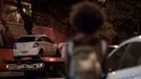 Seorang warga melihat mobil politisi Brasil Marielle Franco yang ditembak di Rio de Janeiro, Brasil (15/3). Penembakan mobil putih tersebut menewaskan Marielle Franco dan sopirnya. (AFP Photo/Mauro Pimentel)