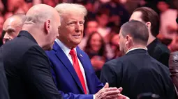 Donald Trump memasuki arena sesaat sebelum dimulainya babak utama dengan didampingi oleh kepala eksekutif UFC, Dana White, pendukung utamanya selama kampanye pemilihan presiden 2024. (Kena Betancur/AFP)