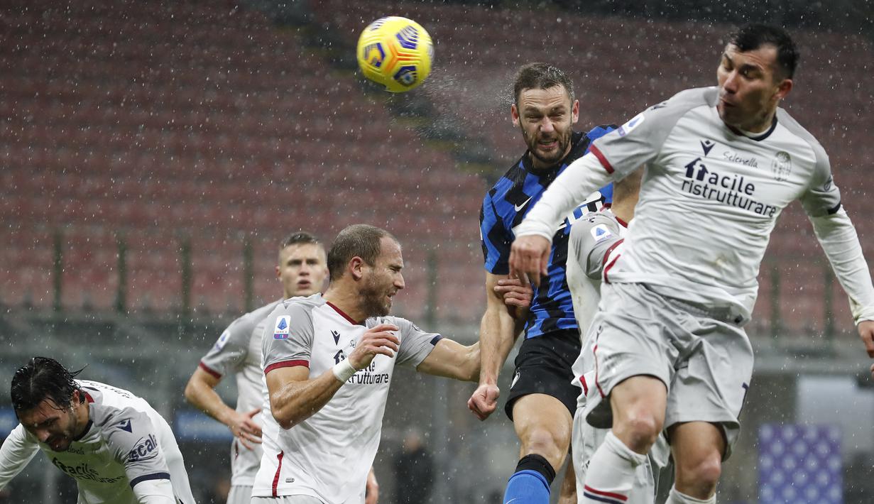 Gelandang Bologna, Gary Medel (kanan), berduel udara dengan bek Inter Milan, Stefan de Vrij (tengah), dalam laga lanjutan Liga Italia Serie A pekan ke-9 di San Siro Stadium, Sabtu (5/12/2020). Bologna kalah 1-3 dari Inter Milan. (AP/Antonio Calanni)