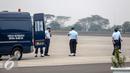 Petugas berjaga di belakang mobil menunggu kedatangan jenazah korban jatuhnya Pesawat Hercules C-130 yang akan tiba di Lanud Halim, Jakarta, Rabu (1/7/2015). Peristiwa nahas tersebut merenggut sekitar 122 korban jiwa. (Liputan6.com/Faizal Fanani)