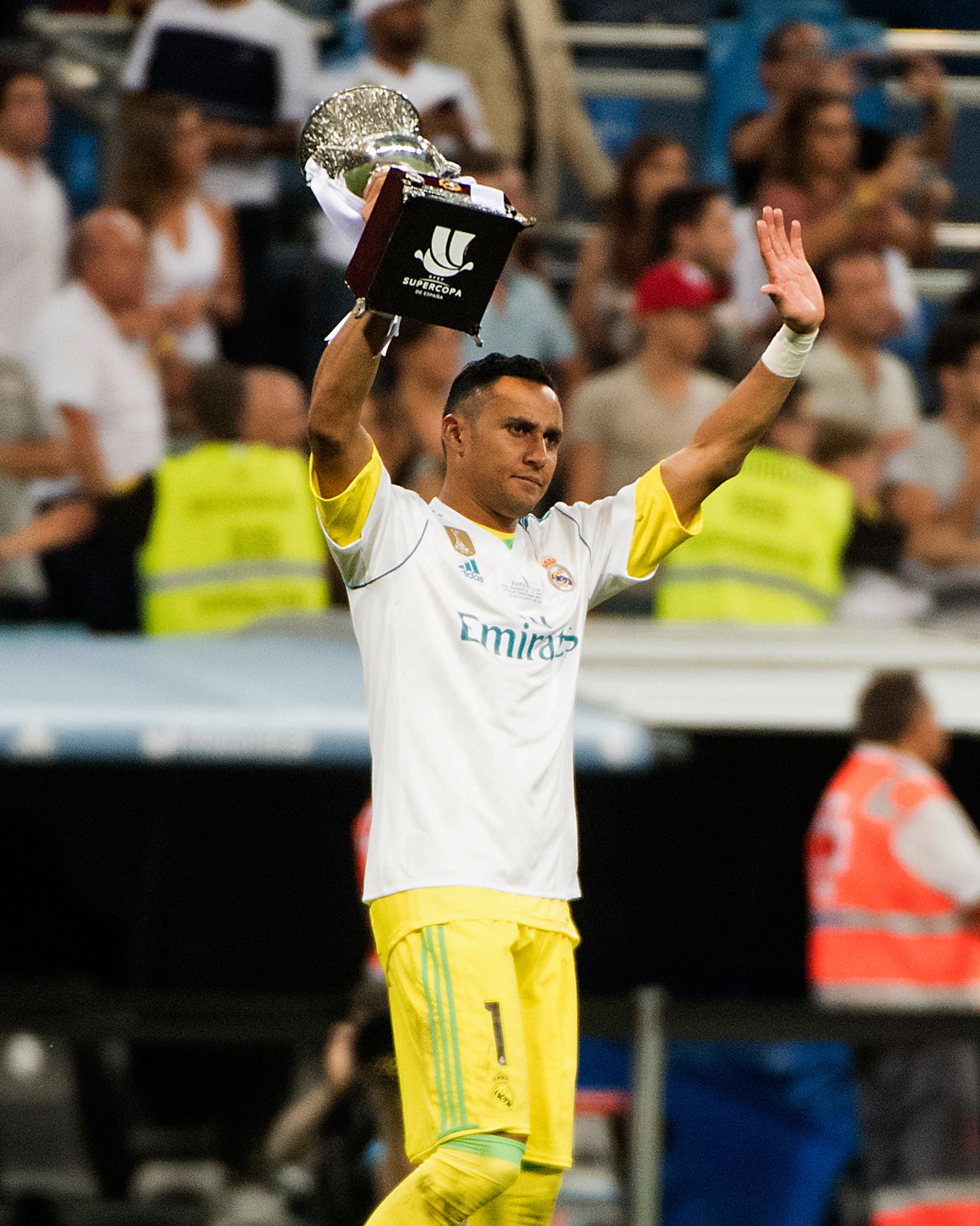 Kiper Real Madrid, Keylor Navas memegang trofi Piala Super Spanyol 2017 usai pertandingan melawan Barcelona di stadion Santiago Bernabeu, Spanyol (16/8). Real Madrid menang 2-0 atas Barcelona dengan skor agregat 5-1. (AFP Photo/Curto De La Torre)