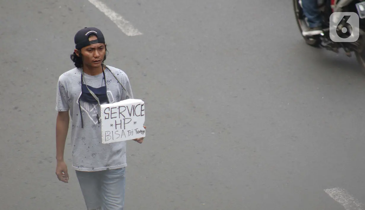 Penjual jasa perbaikan telepon genggam menawarkan jasanya di depan Mall Pusat Grosir Cililitan, Jakarta, Kamis (14/5/2020). Sejak pemberlakuan Pembatasan Sosial Berskala Besar yang berimbas pada penutupan pusat-pusat perbelanjaan, pendapatan mereka turun drastis. (Liputan6.com/Helmi Fithriansyah)