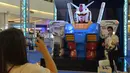 Seorang pelanggan berfoto dengan sebuah model robot mainan Gundam di mal Siam Paragon di Bangkok, Thailand (24/9/2020). Pameran tersebut dibuka pada Kamis (24/9) di mal Siam Paragon dan akan berlangsung hingga 4 Oktober mendatang. (Xinhua/Rachen Sageamsak)