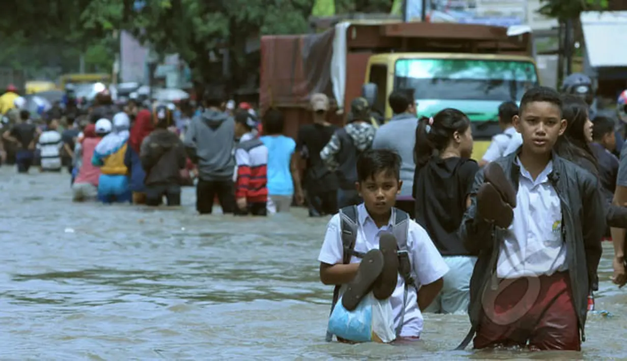 Pelajar berusaha melintasi genangan air ketika banjir merendam Jalan KH Hasyim Ashari, Ciledug, Kota Tangerang, Selasa (10/2/2015). (Liputan6.com/Andrian M Tunay)