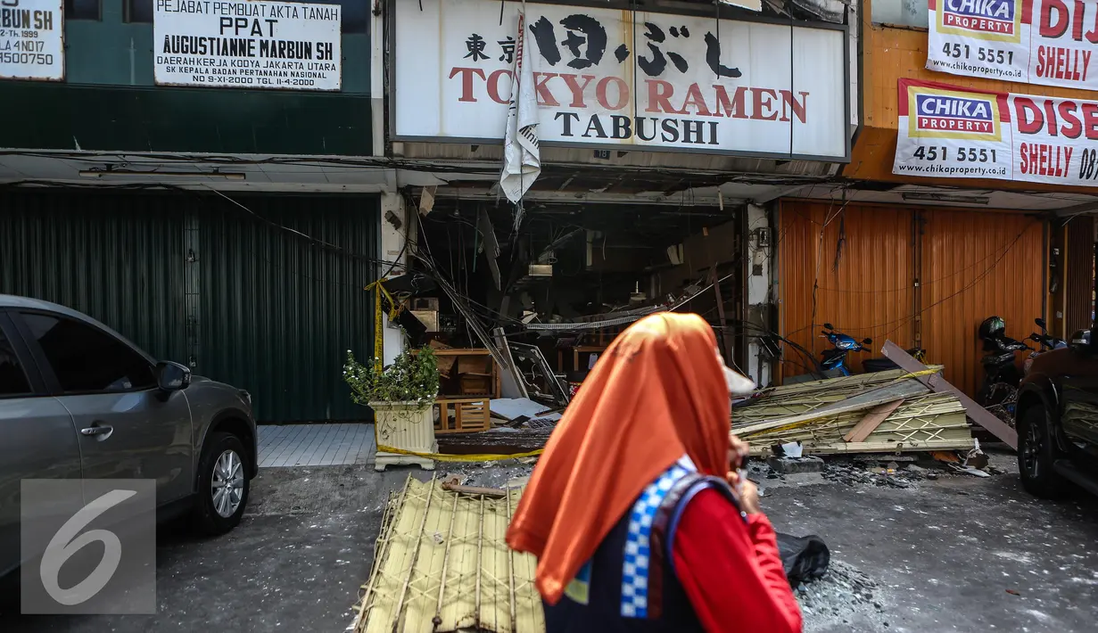 Warga saat melintasi restoran Jepang usai meledak di Jalan Boulevard Raya, Blok IA no 18, Jakarta, pada Senin malam, Selasa (21/7/2015). Ledakan diakibatkan oleh tabung gas yang berada di dapur masak. (Liputan6.com/Faizal Fanani)