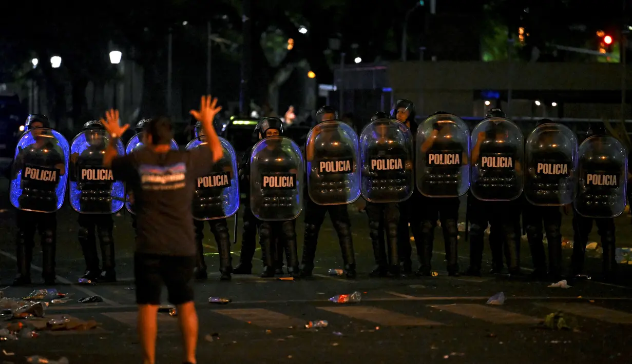 Polisi anti huru hara berjaga-jaga setelah bentrok dengan suporter Argentina setelah perayaan timnas Argentina meraih juara Piala Dunia Qatar 2022 di lingkungan Obelisk di Buenos Aires (20/12/2022). Sebanyak 31 orang terluka. Petugas juga mengamankan 13 orang suporter yang mana 4 di antaranya diamankan di monumen Obelisk. (AFP/Luis Robayo)