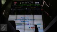 Seorang karyawan berjalan didepan monitor saat peluncuran bank administrator Rekening Dana Nasabah (RDN) Bank Panin di Bursa Efek Indonesia, Jakarta, Rabu (5/4). (Liputan6.com/Angga Yuniar)