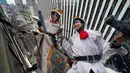 Pembersih jendela wanita berkostum ayam jago dan anjing membersihkan jendela gedung di kawasan perbelanjaan dan bisnis Tokyo, Jepang (20/12). (AP Photo / Shizuo Kambayashi)