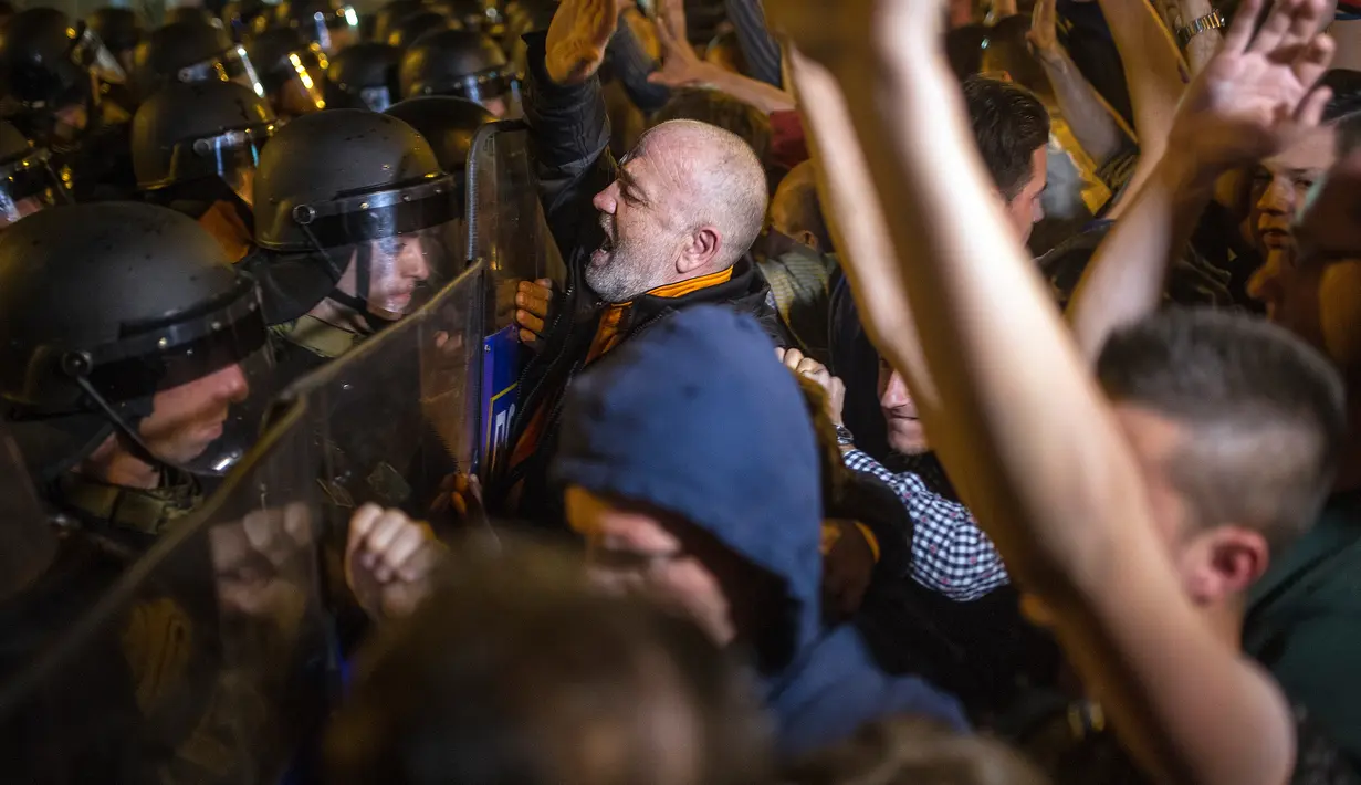 Demonstran berhadapan dengan polisi anti huru hara saat aksi menuntut pengunduran diri Presiden Gjorge Ivanov di Skopje, Makedonia, Rabu (13/4). Mereka memprotes keputusan Presiden memberikan pengampunan bagi 56 politikus (Robert ATANASOVSKI/AFP)