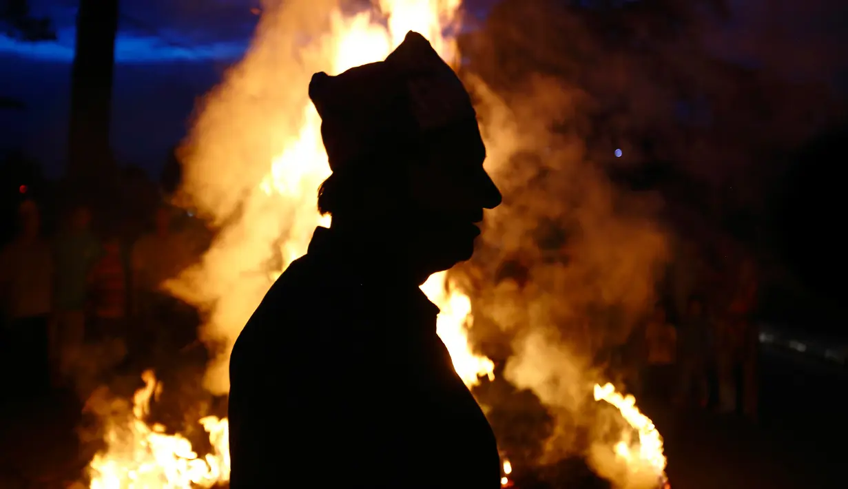 Siluet seorang pria saat mengikuti perayaan membakar jerami Ghanta Karna di Bhaktapur di pinggiran Kathmandu, Nepal (21/7). Festival Hindu in juga dikenal dengan nama Gathemangal. (AFP Photo/Gopen Rai)