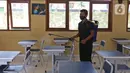 Petugas menyemprotkan disinfektan saat pembelajaran tatap muka terbatas dihentikan diganti dengan pembelajaran jarak jauh di SMPN 2 Depok, Pancoran Mas, Depok, Jawa Barat, Jumat (19/11/2021). (Liputan6.com/Herman Zakharia)