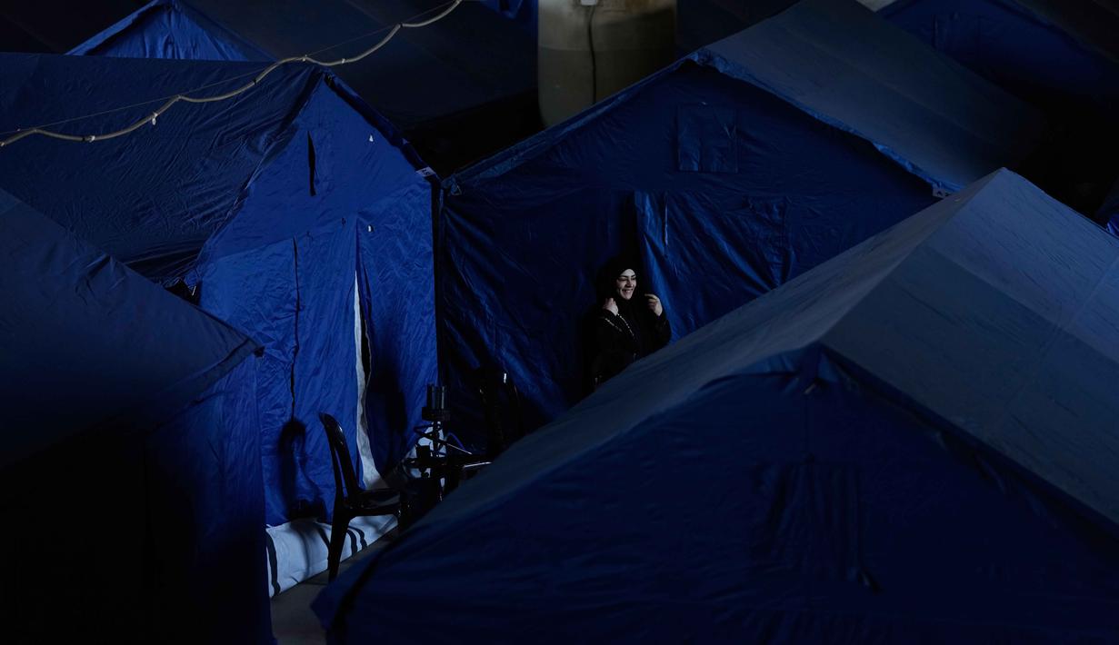 Seorang wanita pengungsi berdiri di samping tenda-tenda yang didirikan di dalam Camille Chamoun Sports City Stadium, yang telah diubah menjadi tempat penampungan bagi orang-orang yang melarikan diri dari serangan udara Israel di Lebanon selatan, Beirut, Lebanon, Rabu 8 April 2026. Serangan Israel yang terus berlanjut memaksa pihak berwenang Lebanon membuka Stadion Camille Chamoun Sports City di Beirut sebagai salah satu lokasi penampungan. (AP Photo/Bilal Hussein)