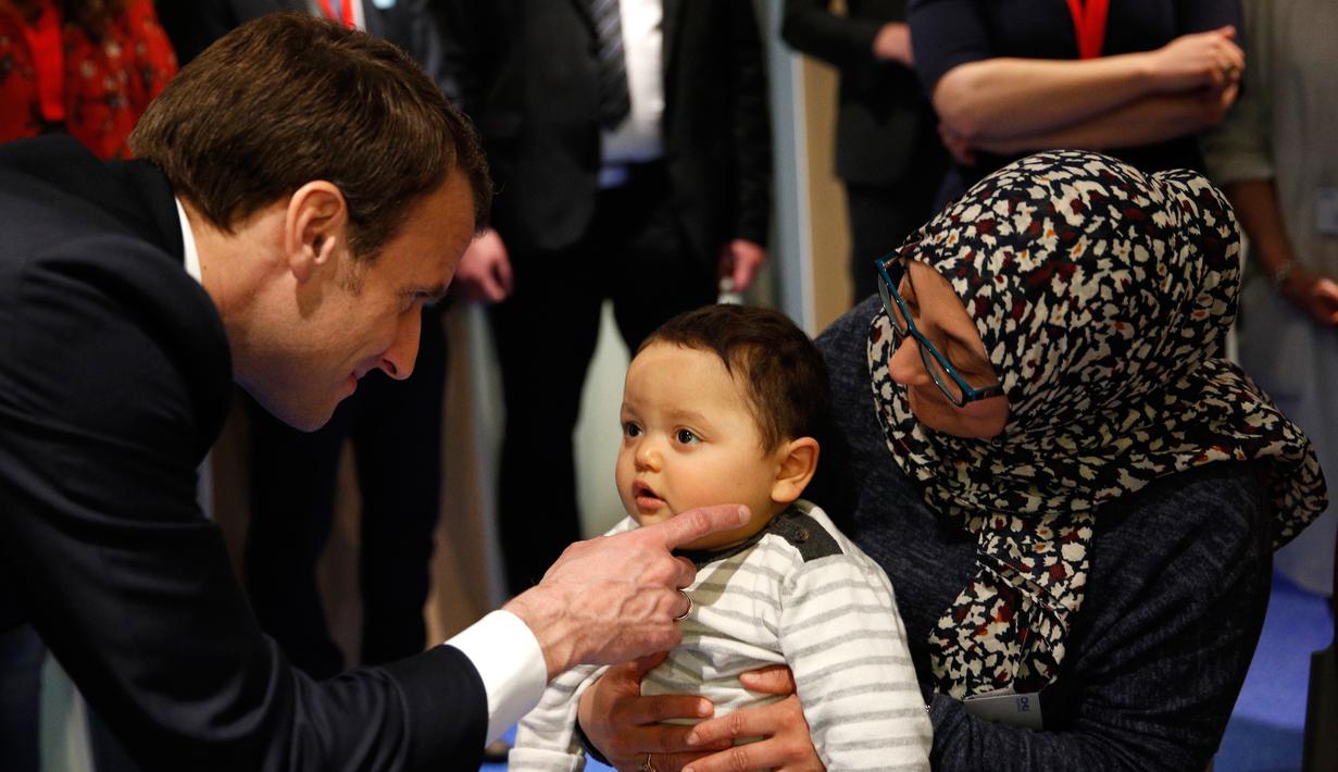 Presiden Prancis Emmanuel Macron menghibur seorang anak saat mengunjungi Graffiti's- Association Le Moulin Vert di Normandia, Prancis (5/4). Pada kunjungannya Presiden Emmanuel Macron berinteraksi dengan anak-anak autis. (AP / Christophe Ena, Pool)