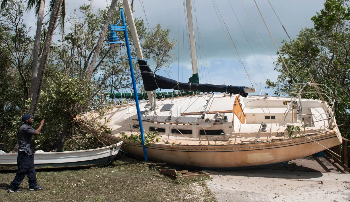 Seorang pria mengambil gambar sebuah kapal yang terhempas ke daratan akibat terhempas badai Irma di Coconut Grove, Florida, Senin (11/9). Badai Irma menghantam negara bagian Florida dengan kecepatan angin mencapai 200 km/jam. (SAUL LOEB/AFP)