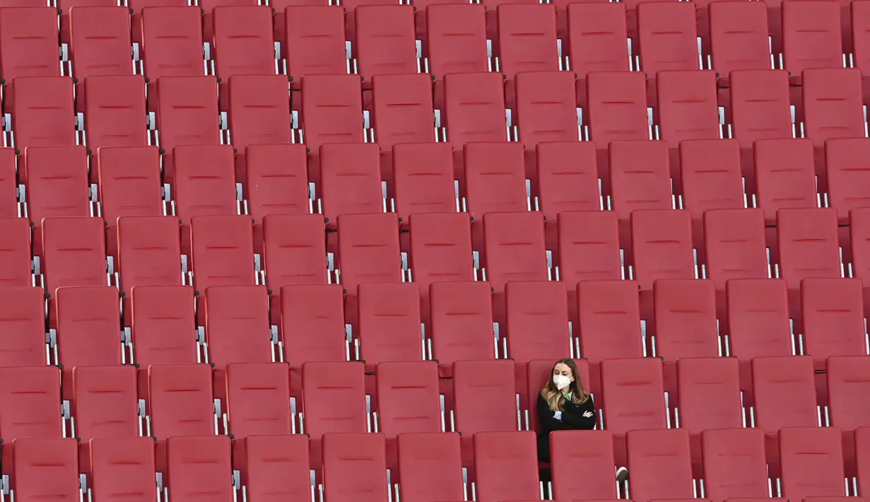 Seorang wanita duduk di tribun penonton yang kosong dalam pertandingan Liga Jerman antara Augsburg melawan Bayer Leverkusen, Minggu (21/2/2021). (Foto: AFP/Berbagai Sumber/Christof Stache)