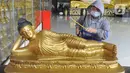 Umat menyemprotkan cairan disinfektan ke patung Buddha tidur di Vihara Buddha Dharma dan 8 Posat, Bogor, Jawa Barat, Minggu (7/2/2021). Ritual pencucian patung dan bersih-bersih ini dilakukan dalam rangka menyambut perayaan tahun baru China atau Imlek. (merdeka.com/Arie Basuki)
