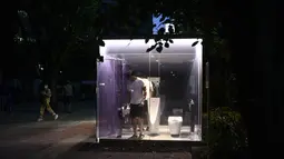 Seorang pria menggunakan toilet transparan di Haru-no-Ogawa Community Park di distrik Shibuya, Tokyo (19/8/2020). Toilet ini dirancang oleh Shigeru Ban dimana dinding luar kacanya akan berubah menjadi buram ketika kuncinya ditutup. (AFP Photo/Philip Fong)